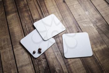Blank white beer coasters and coffee beans on wood table background.