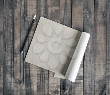 Blank brochure or notepad of kraft paper and pencil on wood background. Flat lay.