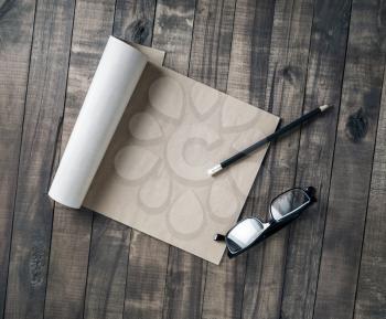 Blank notebook of kraft paper, glasses and pencil on wood background. Flat lay.