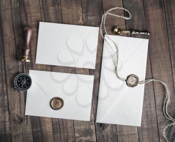 Vintage letter envelopes with wax seal, stamp, spoon, magnifier, compass and postcard on wood background. Flat lay.