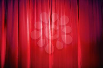 Bright red stage curtain with spotlight. Abstract background.