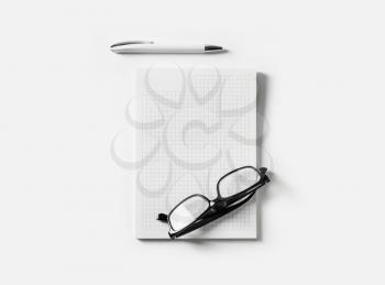 Blank copybook, glasses and pen on white paper background. Flat lay.