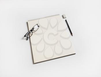 Sketchbook and stationery. Blank notebook, glasses, pencil and eraser on white paper background.