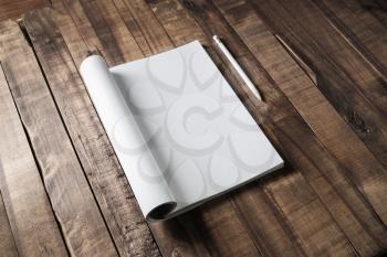 Magazine, brochure or booklet with blank pages and white pencil on wood table background.