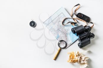 Travel plan background. Map, binoculars, compass, magnifier and crumpled paper on white paper background. Flat lay.