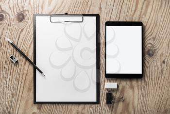 Photo of blank stationery and tablet on wood background. Flat lay.