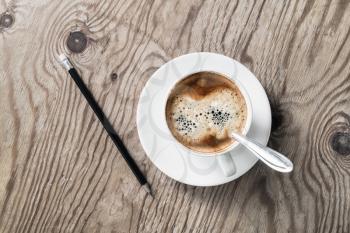 Photo of coffee cup and pencil on wood background.