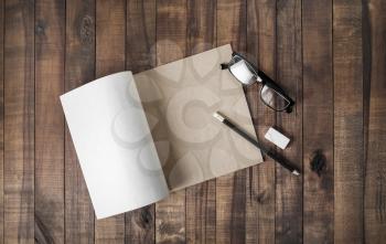 Blank notepad and stationery: glasses, pencil and eraser on wooden background. Flat lay.