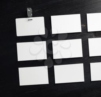 Blank white business cards and badge on wood table background. Flat lay.