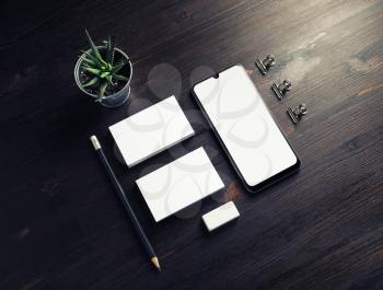 Business brand template. Smartphone, business cards, pencil, eraser and plant on wood table background.