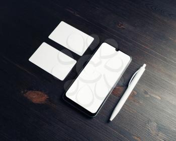 Smartphone, blank business cards and pen on wooden background. Responsive design mockup.