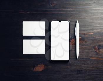 Blank business template. Smartphone, blank business cards and pen on wood table background. Flat lay.