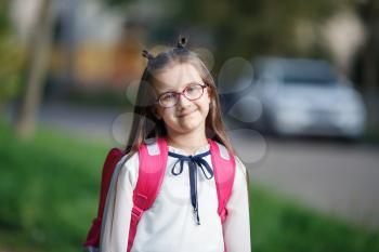 Portrait of smiling schoolgirl with backpack outdoors. Child girl looking at camera. Selective focus.