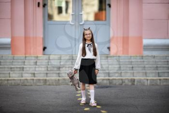 Child girl with plush toy against school background. Back to school. Selective focus.