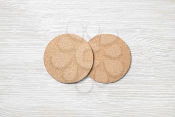 Two blank cork beer coasters on light wooden background. Responsive design template. Flat lay.