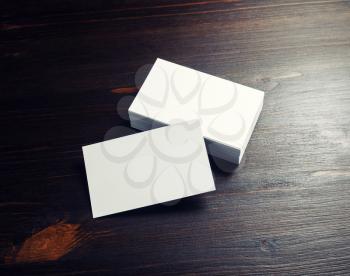 Photo of blank white business cards on dark wooden background.