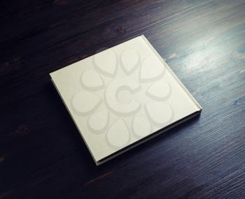 Photo of blank hardcover booklet on dark wood table background.