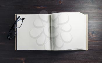 Photo of blank book and glasses on dark wooden background. Copy space for text. Flat lay.