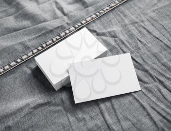 Blank white business cards on gray denim background.