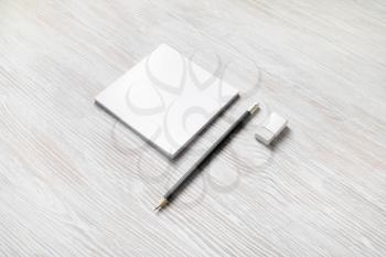 White square notepad, pencil and eraser on light wooden background. Blank stationery template.