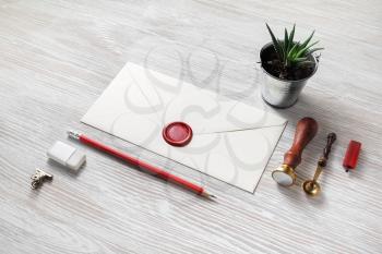Blank paper envelope with red wax seal and stationery on light wooden background. Mockup for your design.