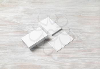 Three blank business cards on light wooden background. Branding mockup. Copy space for text.