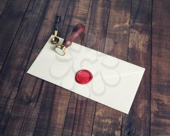 Old letter envelope with red wax seal and stamp on wooden background.