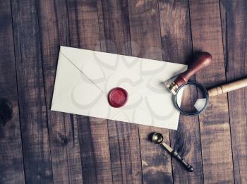 Old envelope with red wax seal, magnifier and stamp on wood table background. Flat lay.