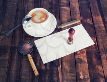 Blank retro stationery set on wood table background. Envelope, magnifier, coffee cup, stamp and spoon.