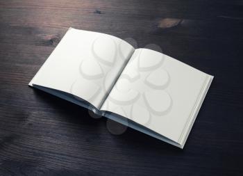 Open booklet with blank pages on wooden background.