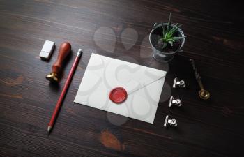 Vintage letter envelope with wax seal, stamp, pencil, eraser, plant and spoon on wood table background. Mock-up for your design.