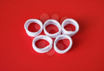 White fabric bracelets in the form of olympic rings on red background.