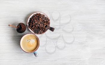 Coffee cup and coffee beans on light wooden background. Copy space for your text. Flat lay.