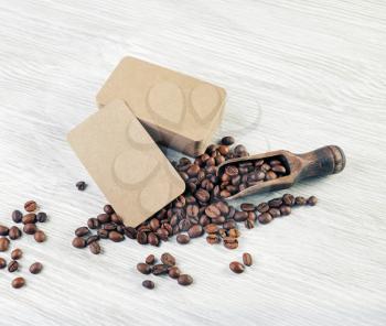 Photo of blank kraft paper business cards and roasted coffee beans on light wooden background. Mockup for your design.