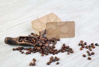 Roasted coffee beans and vintage kraft paper business cards over light wooden background.
