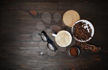 Coffee cup, roasted coffee beans, coffee ground, beer coaster and glasses on wood table background. Flat lay.