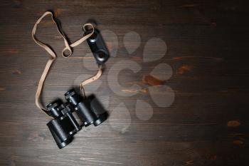 Old black military binocular on wood table background. Copy space for your text. Flat lay.