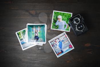 Square photos and vintage camera on wood table background. Flat lay.