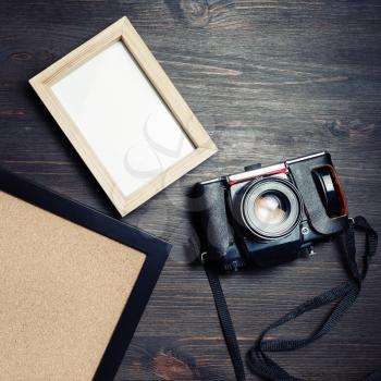 Vintage camera and blank photo frames on wood table background. Flat lay.
