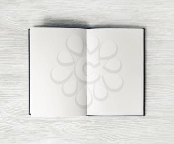 Photo of opened book with blank white pages on light wooden background. Responsive design mockup. Top view. Flat lay.