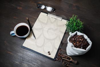Coffee and blank menu. Clipboard with blank kraft letterhead, coffee cup, coffee beans, plant, glasses and pencil on wood table background.