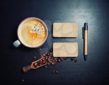 Blank kraft business cards, coffee cup, coffee beans and pen on black wooden backgroundFlat lay.