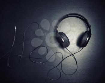 Photo of black headphones or headset on black wood table background. Flat lay.
