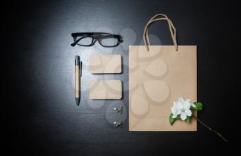 Photo of blank kraft paper stationery set and flowers on black table background. Top view. Flat lay.