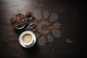 Coffee cup, roasted coffee beans and ground powder on old wooden kitchen table background. Top view. Flat lay.