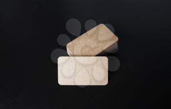Kraft business cards mockup on black wooden background. Copy space for text.