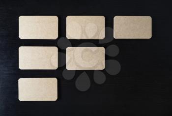 Blank kraft business cards on black wood table background. Template for branding identity. Flat lay.