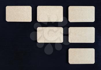 Photo of blank vintage business cards on black wooden background. Flat lay.