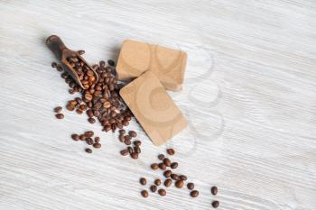 Blank vintage business cards and roasted coffee beans on light wooden background. Copy space for your text.