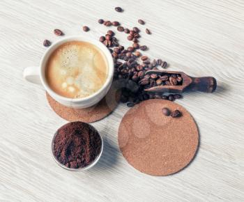 Delicious fresh coffee. Coffee cup, coffee beans, beer coaster and ground powder on light wooden background. Flat lay.